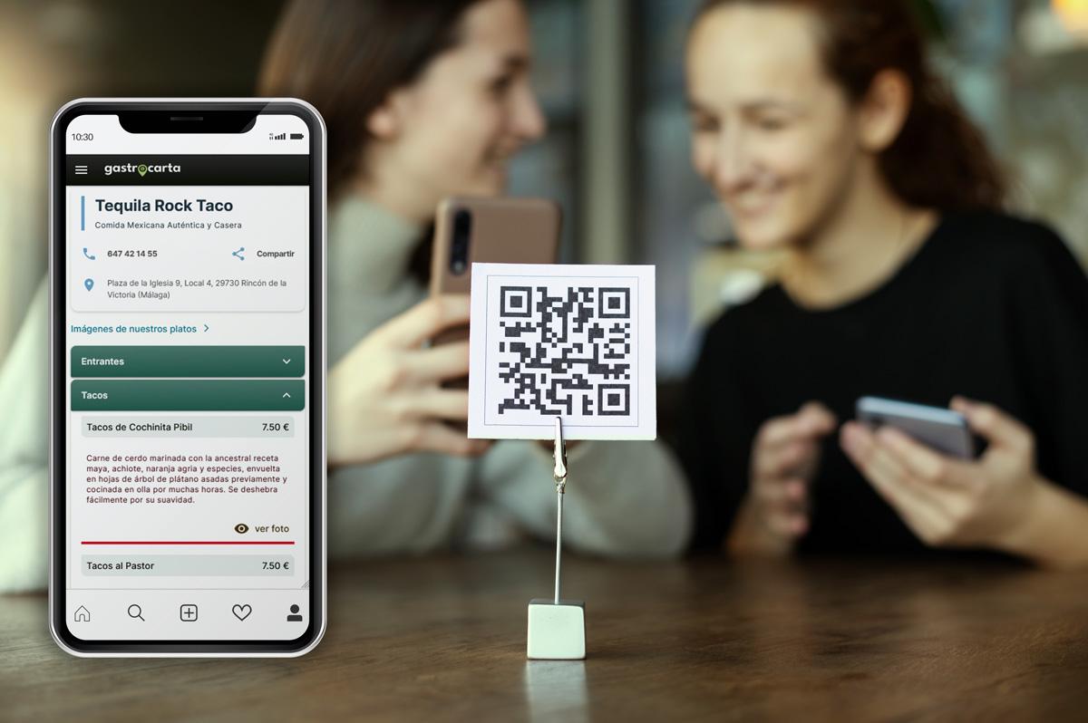 Imágen de dos jóvenes en un restaurante mirando la carta online, un código QR y un móvil con la aplicación de gastrocarta