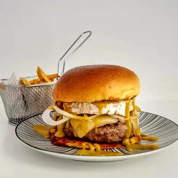 Burger Cabrón Pan brioche, carne de 200g 100% vacuno en medallón, queso premium rulo de cabra, queso gouda, lechuga, cebolla a la plancha, salsa miel y mostaza casera, acompañadas de patatas fritas naturales