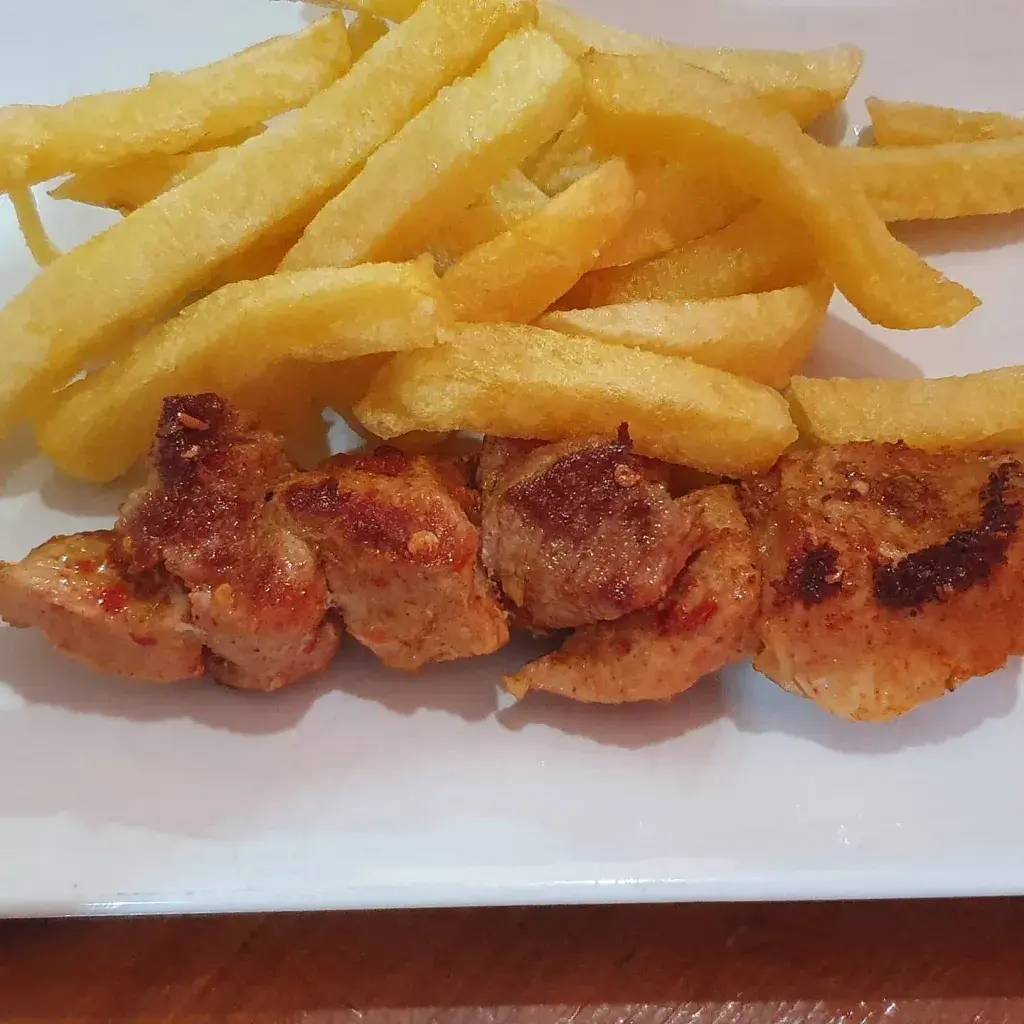 PINCHITO DE CERDO O POLLO Con aliño picante casero y servido con patatas fritas caseras.