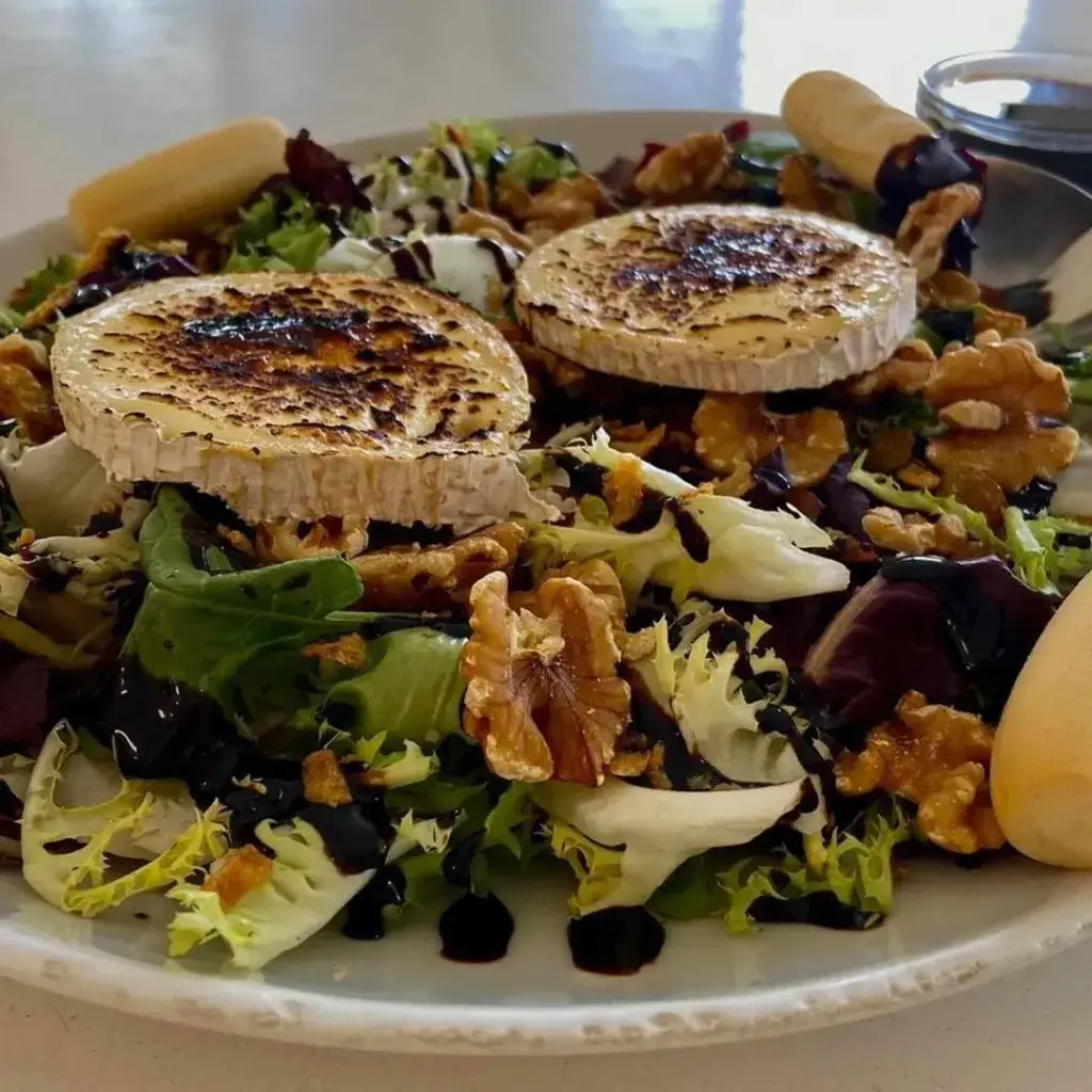 Ensalada queso de cabra Mezclum, nueces, pasas, cebolla frita, miel de caña, vinagre de módena, piquito, queso de cabra