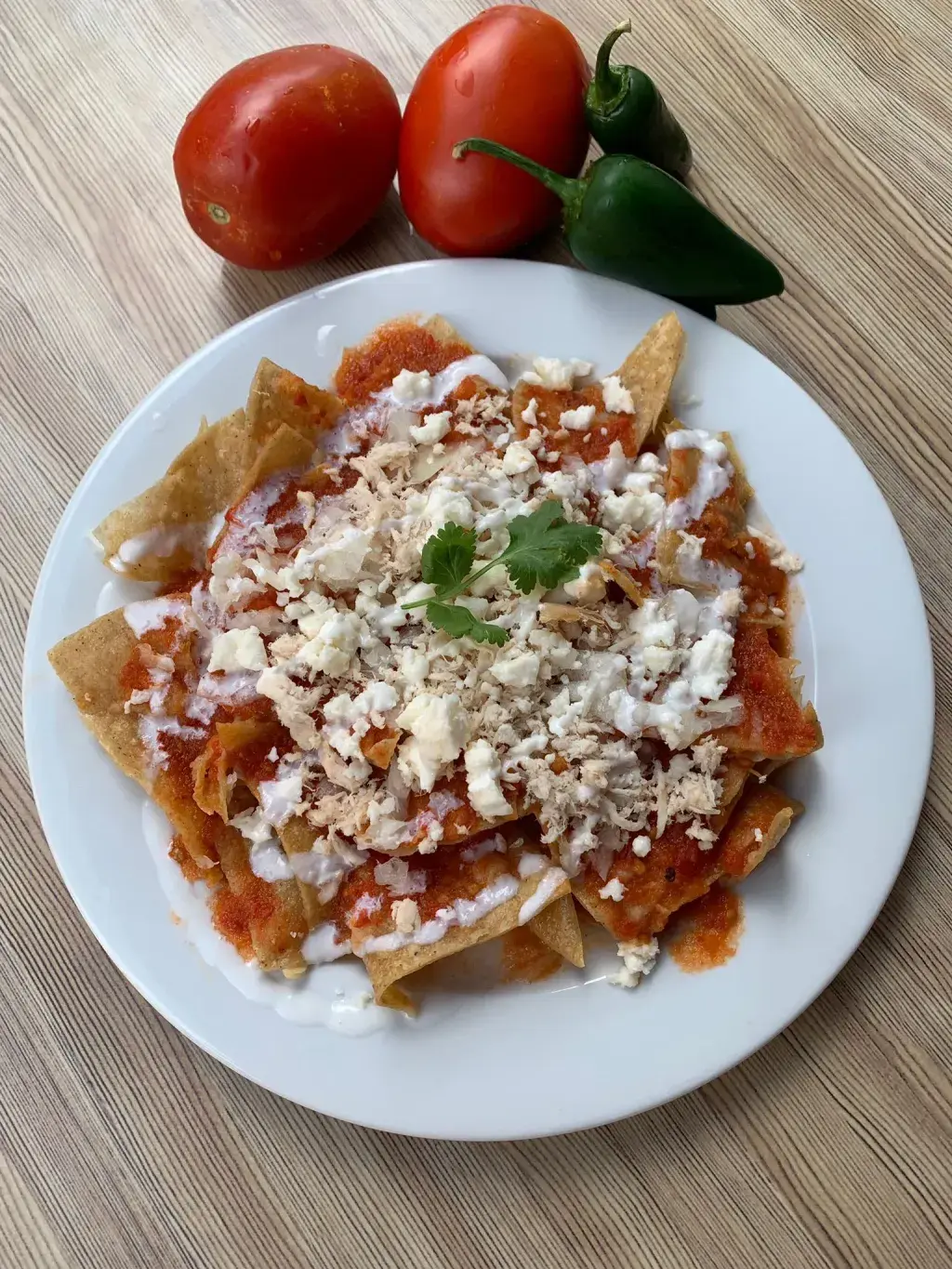 Chilaquiles Rojos de Pollo o Chorizo Los chilaquiles son un plato típico mexicano elaborado a base de tortillas cortadas, fritas o tostadas (o al natural), que se cocinan en una salsa verde o roja con un ligero picante. Hay muchísimas cosas que se pueden añadir. En Tequila Rock Taco los tenemos con pollo o chorizo. e les añade crema (nata), queso campero  y cebolla picada.