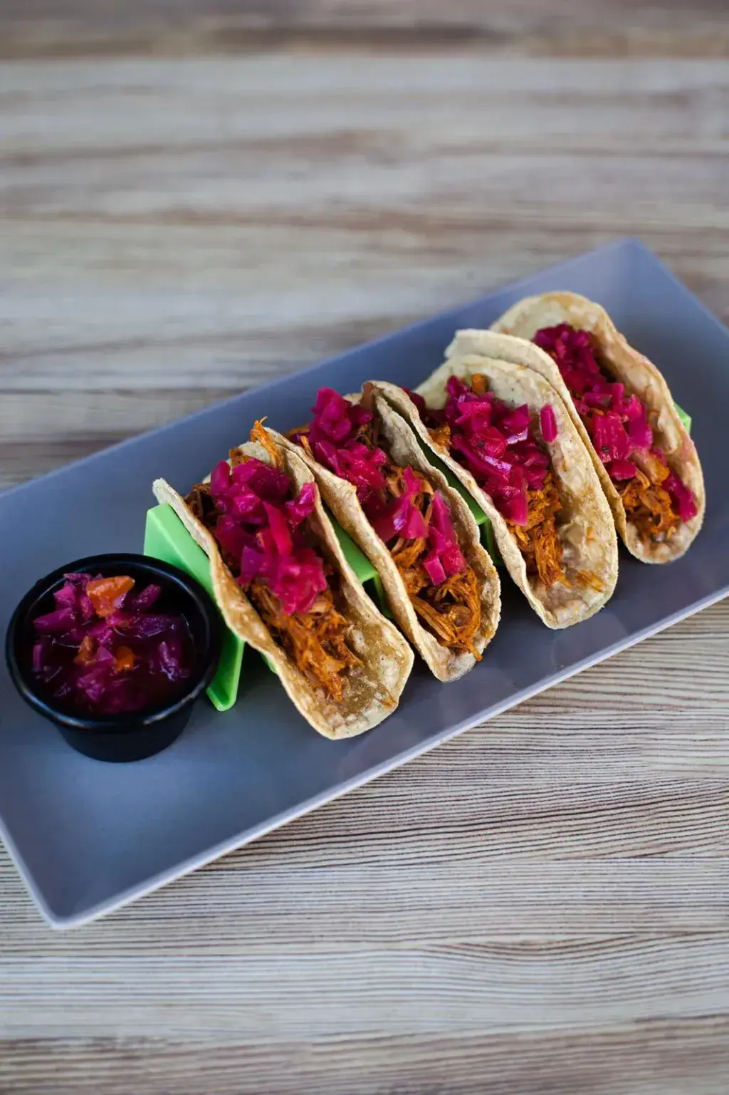 Tacos de Cochinita Pibil Carne de cerdo marinada con la ancestral receta maya, achiote, naranja agria y especies, envuelta en hojas de árbol de plátano asadas previamente y cocinada en olla por muchas horas. Se deshebra fácilmente por su suavidad.