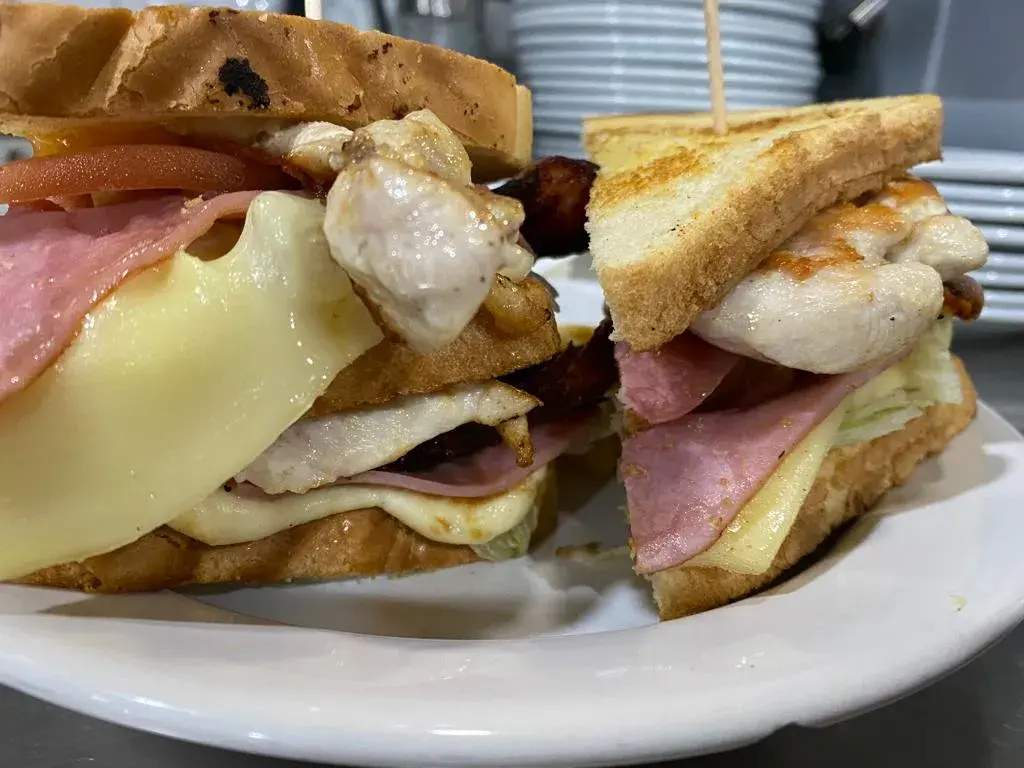 Sandwich Club Dos pisos de pollo, jamón york, bacon, queso Edam, lechuga, tomate y mayonesa